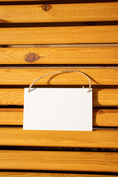 white hanging picture sign on golden wooden chair slats with empty free space for template or blank copy area