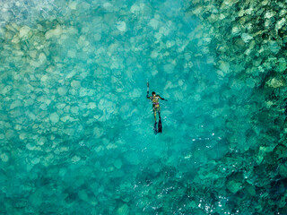 Aerial drone view of a person doing spearfishing on crystal blue water. Recreational fishing and...