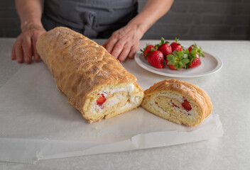Fresh baked and filled swiss roll with whipped cream and strawberry filling on kitchen counter without topping