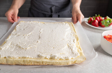 Sponge cake base spread with whipped cream for making a swiss roll
