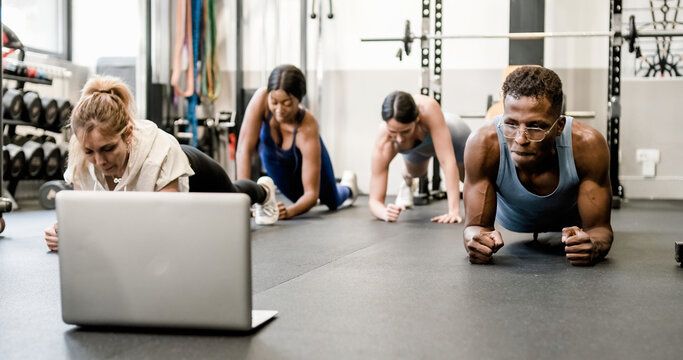 Multiethnic sportspeople exercising online via laptop in gym - Powered by Adobe
