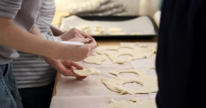 Midsection of caucasian young mother with daughters creating patterns on dough with fork while making cookies on table in kitchen Generative AI