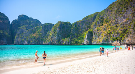 Fototapeta premium THAILAND, PHI PHI ISLAND, 12, April 2023.Tourists enjoying on the Maya Bay, Ko Phi Phi Leh island, part of Krabi, Thailand. View round with steep limestone hills and emerald green water.