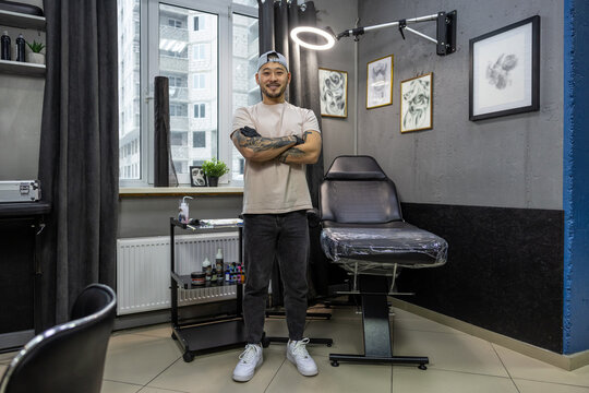 Asian young man standing in the tattoo salon