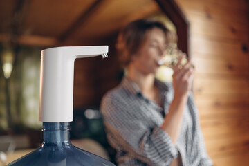 automatic water pump. A woman is drinking water. Blurred background. Space for text.
