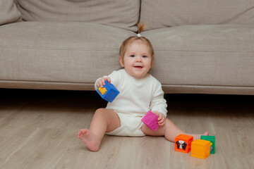 baby girl sitting at home on the floor playing cubes, child development