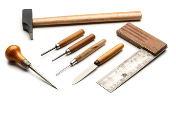 Herramientas de trabajo, gubias, martillo, cuchillo, punzón y madera sobre un fondo blanco liso y aislado. Vista superior y de cerca. Copy space
