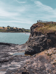 Fototapeta na wymiar A sheer stone cliff on the Atlantic Ocean in Ireland on a sunny summer day. Irish seaside landscape, clear blue sky, rock formation near water.
