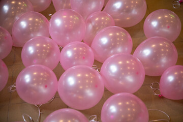 Pink heavily inflated balloons lie on the floor of ceramic tiles.