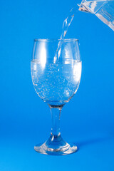 Pour the water from the jug into the wine glass.