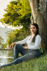 Obraz premium vertical shot of a beautiful female college student sitting to the side with a golden sunset in the background