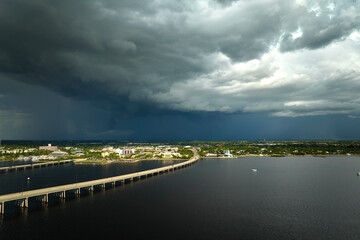 Obraz premium Heavy thunderstorm approaching traffic bridge connecting Punta Gorda and Port Charlotte over Peace River. Bad weather conditions for driving during rainy season in Florida