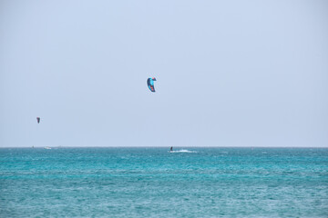 People sportsmen windsurfing and kite surfing in blue ocean water. Summer extreme exotic sport concept