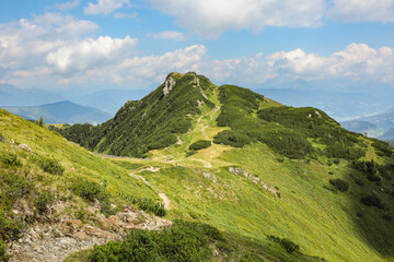 Fototapeta na wymiar Green Hilly Mountain in Austria. Alpine View of Grass Landscape in Flachau during Summer Day. Outdoor Panorama of European Landscape.