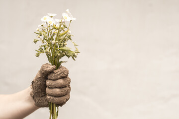 muddy hand holding a bouquet of flowers