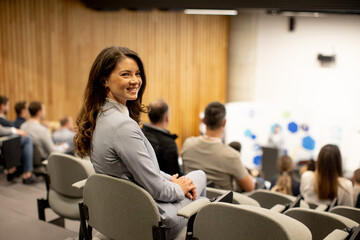 Young woman sitting in audience on conference or workshop