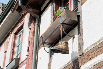 Two mountain boots hanging from a flower box at the window of an old half-timbered house in the old...