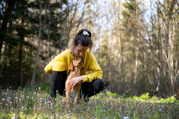 Female dog owner kneeling down to cuddle with her golden labrador retriever puppy