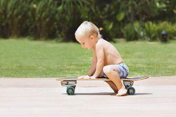 Funny skateboard riding. Little child with surf skateboard have fun in beach skate park. Active family lifestyle, outdoor activities on summer holidays in city. Kids recreational sports.