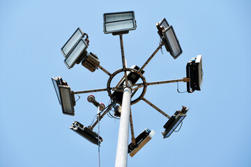 High mast lighting pole lights. Round sport light with blue cloud sky background.