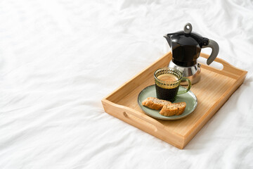 coffee in bed. a cup of coffee and a coffee maker on a wooden tray.