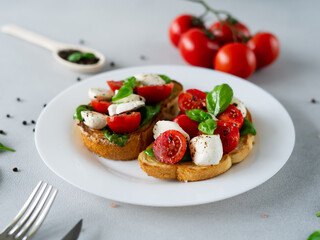 Toast with mozzarella cheese, tomatoes and basil leaves on light background. Italian food