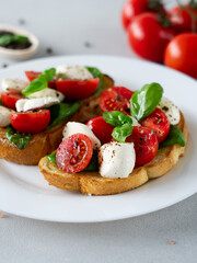Close-up of Bruschetta with tomatoes, mozzarella and basil leaves on light background. Crostino Caprese