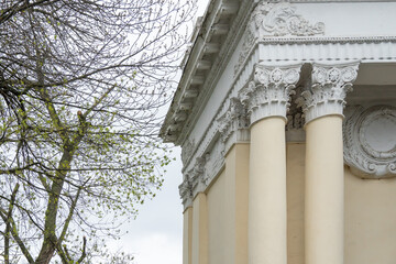 Architectural columns with figures and white stucco wealth. Solemn entrance to city park is made in...
