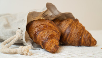 Croissants on gray bag on rustic table. Freshly baked croissants in sustainable linen bag.