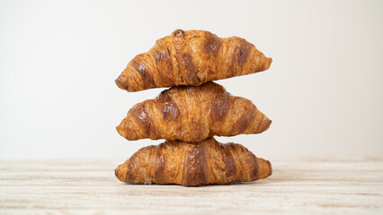 Stack of freshly baked croissants on wooden table. Home-made buttery croissants stacked on top of each other on brown table.