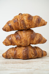 Freshly baked croissants on wooden table. Home-made buttery croissants on brown table.