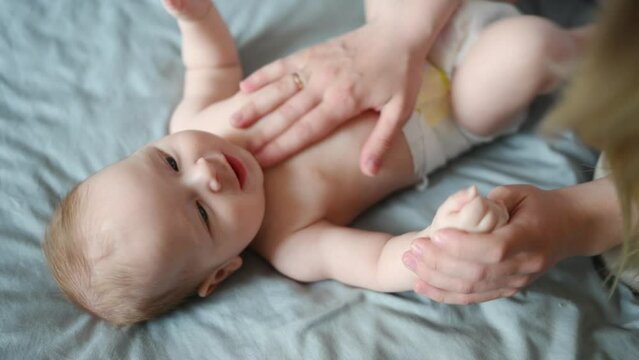 Mom massages the baby tummy with her hand. Children massage. Nanny, maternity leave,colic, massage therapist concept Generative AI