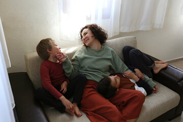 Adult woman enjoying weekend at home and spending quality time with her two sons. Indoor activity with children concept. Close up, copy space, background.