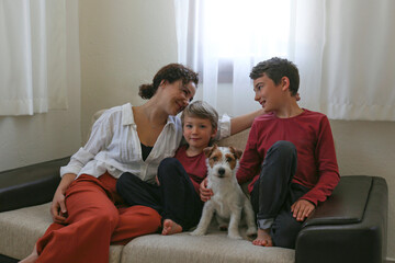 Adult woman enjoying weekend at home and spending quality time with her two sons and a jack russell terrier pup. Close up, copy space, background.