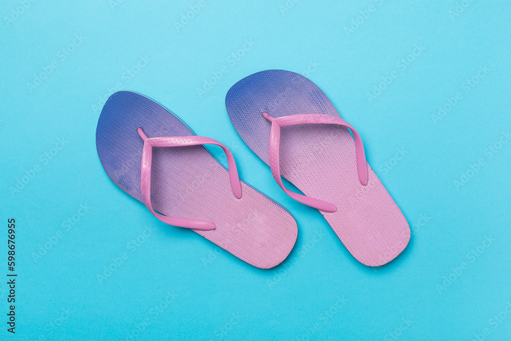 Wall mural Bright flip flops on color background, top view