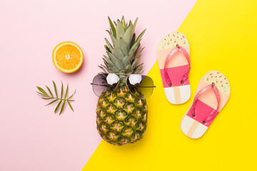 Creative pineapple hipster in sunglasses on color background, top view