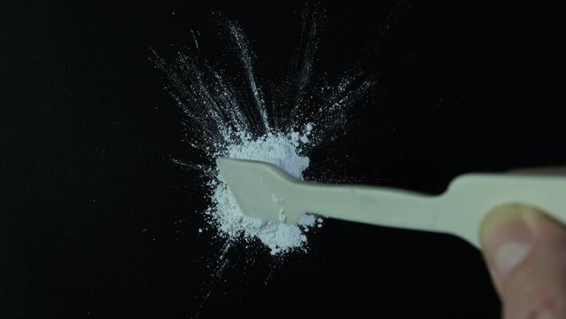 Pile of Titanium dioxide on dark surface. TiO2, White chemical powder. Food additive E171. Clockwise rotation. Titanium dioxide used in cosmetic, medicine, and skin care products.