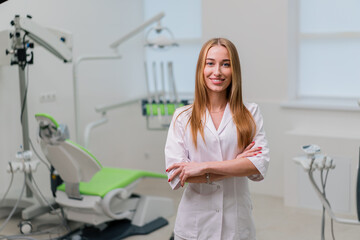 Obraz premium portrait of a beautiful young smiling doctor dentist standing in the dental office before the procedure