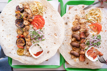 Grilled kebab with pita bread and vegetables on tray in summer fast food street cafe, top view