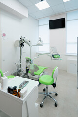 empty modern white and green dentist's office in clinic with computer equipment professional dental chair