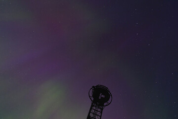 green and purple aurora borealis in the night starry sky