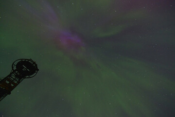 green and purple aurora borealis in the night starry sky