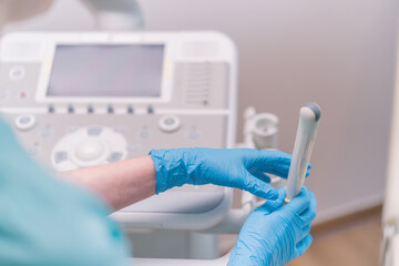 A gynecologist holds a transvaginal ultrasound device in his hands for diagnosing a patient in the...