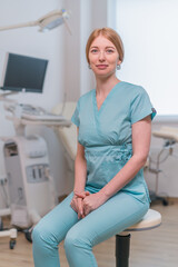 smiling doctor gynecologist sits in gynecological office near ultrasound machine and gynecological chair waiting for patients