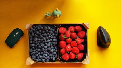 Minimalistic poster of food and technology. Basket filled blueberries and strawberries.