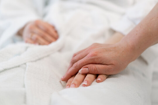 A doctor's hands holding a patient's hands as a sign of care and support close-up in a hospital room