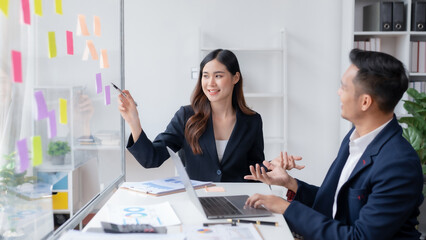 Two asian business people discuss with new startup project Idea presentation, analyze planning at office.