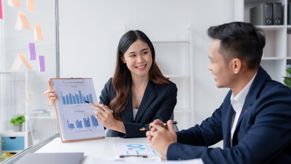 Two asian business people discuss with new startup project Idea presentation, analyze planning at office.