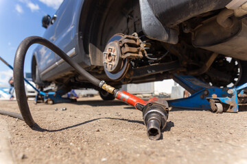Car on tire mounting with removed wheel on pneumatic jack, seasonal tire change, car service concept.