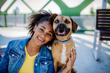 Portrait of happy multiracial girl with her dog. Concept of relationship between dog and teenager,...